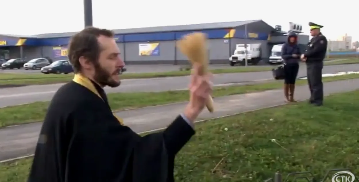 Сотрудник ГАИ наблюдает, как священник освящает участок дороги / Скриншот с видео солигорского телеканала
