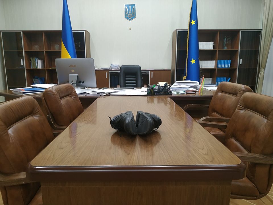 Міністр юстыцыі Украіны падпісвае дакумент, схаваўшыся пад сталом