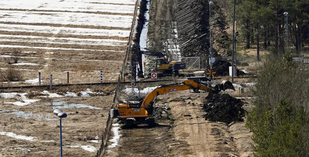 Экскаваторы копают песок возле пограничного забора с Россией / Reuters
