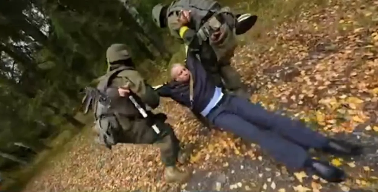 Бойцы с желтыми повязками тянут " убитого" милиционера в лес / Скриншот из видео МВД
