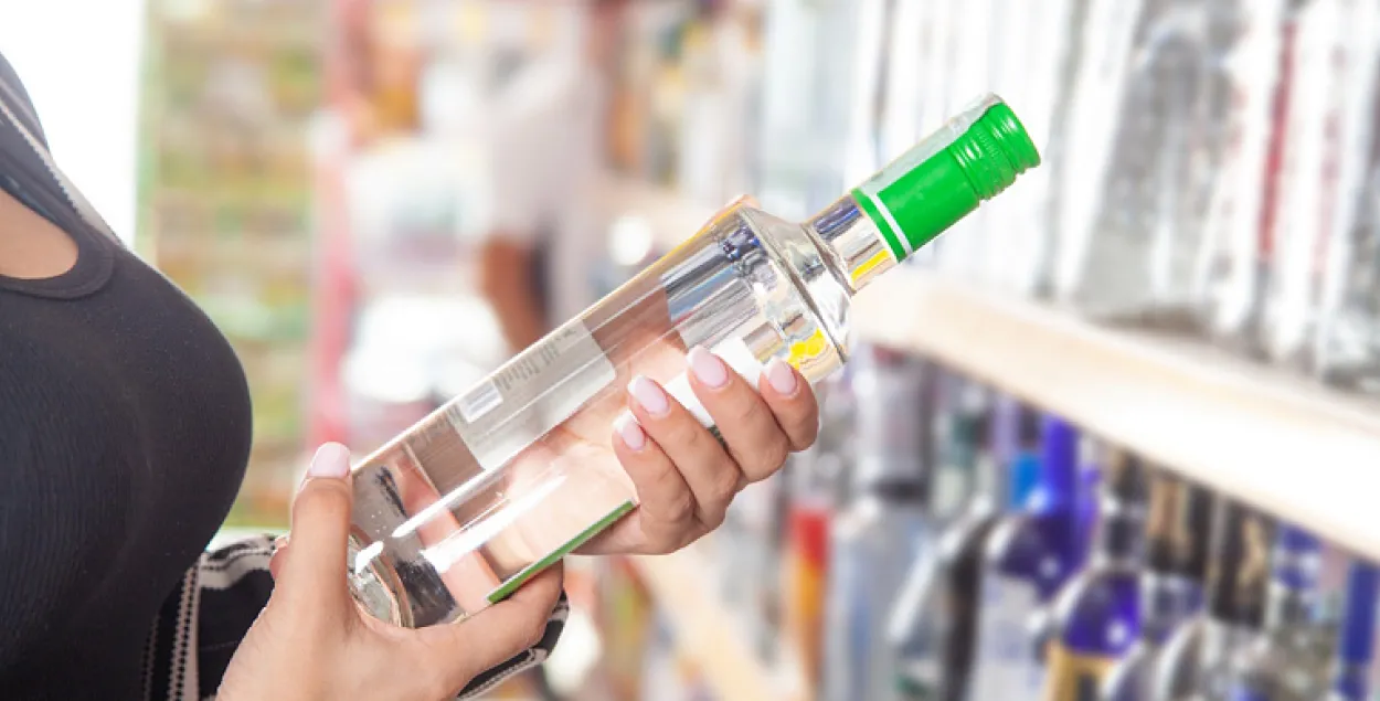 Женщина держит в руках бутылку алкоголя
