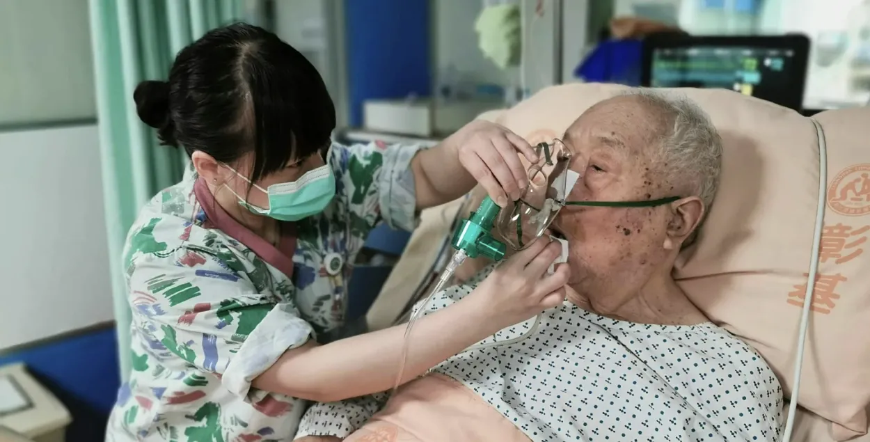 Медсестра вытирает рот госпитализированному пожилому мужчине
