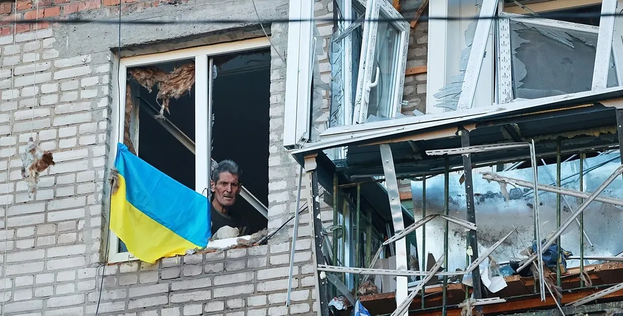 Украинец с флагом в окне разрушенного дома
