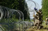 Литовские военные строят барьер из колючей проволоки на границе с Беларусью. Июль 2021-го / Reuters​