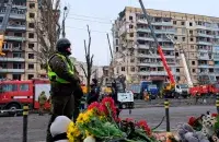 Люди несут цветы, свечи и игрушки к разрушенному зданию в Днепре / RFE/RL

