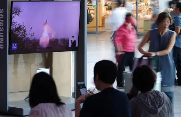 Пассажиры на вокзале в Сеуле смотрят репортаж о запуске баллистической ракеты КНДР / Reuters
