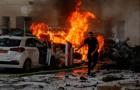Мужчина убегает от огня после ракетного удара в Ашкелоне