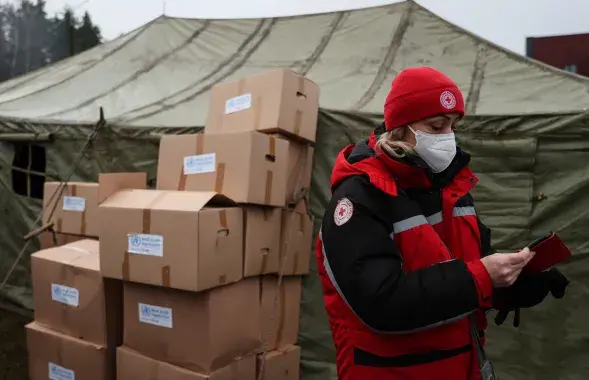 Работница белорусского Красного Креста рядом с гуманитарной помощью