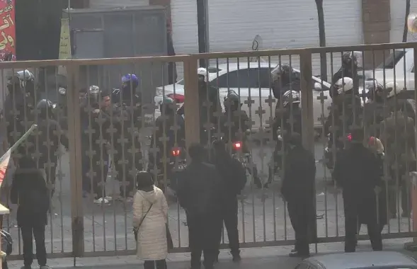 Сілавікі стаяць за варотамі бальніцы ў Тэгеране, дзе, паводле відавочцаў, некаторыя пратэстуючыя шукалі прытулак падчас сутыкненняў 6 студзеня 2026 года
