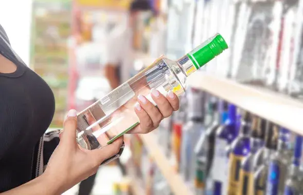 Жанчына трымае ў руках бутэльку алкаголю
